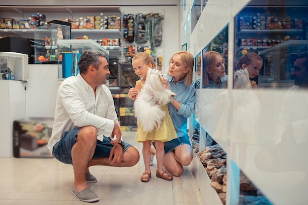 Dochter met pluizige hond op bezoek bij aquarium met mama en papa