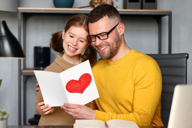 Dochtertje van een klein meisje dat op Vaderdag een verrassing voor papa maakt en hem een handgemaakte ansichtkaart geeft