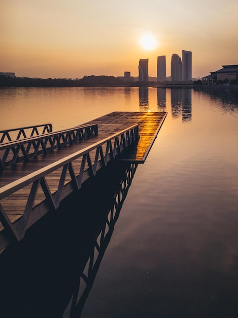 Photo a dock in a lake with a sunset in the background