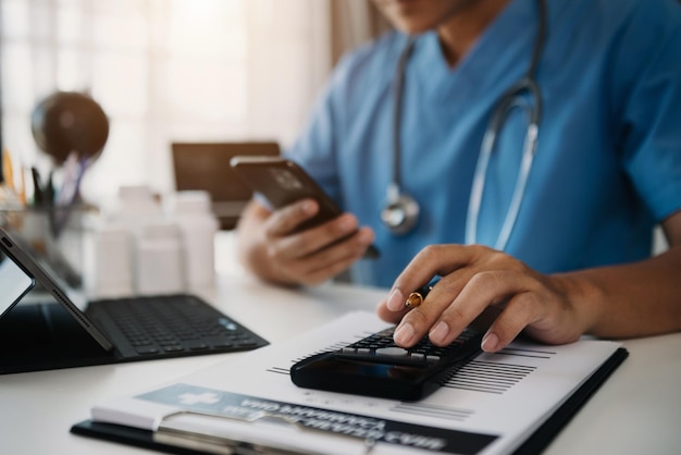 Doctor or accounting department writes a note and uses a calculator to calculate expenses income of hospital staff