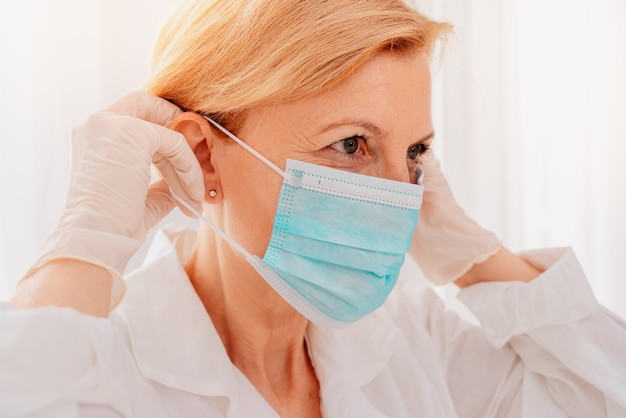 의사는 코로나 바이러스로부터 자신을 보호하기 위해 안면 마스크를 조정합니다.
