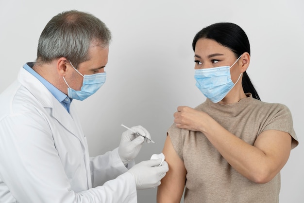 Photo doctor administering vaccine shot to female patient
