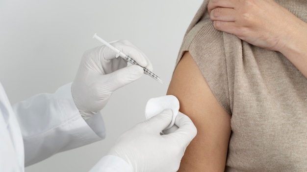 Photo doctor administering vaccine shot to female patient