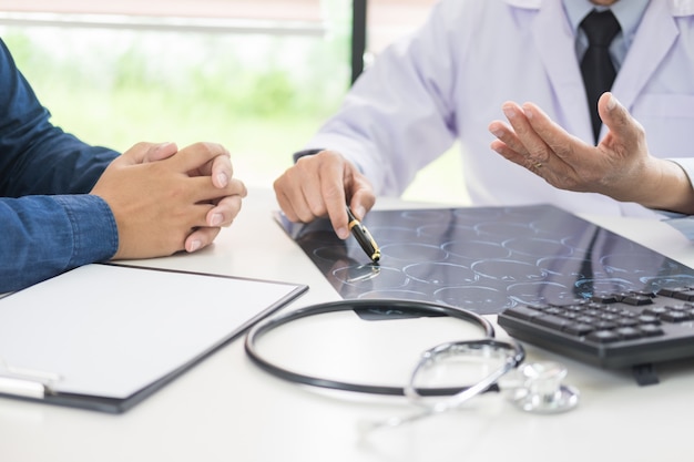 Doctor analysing a scan or x-ray film explain a CT scan talking to patient treatment brain