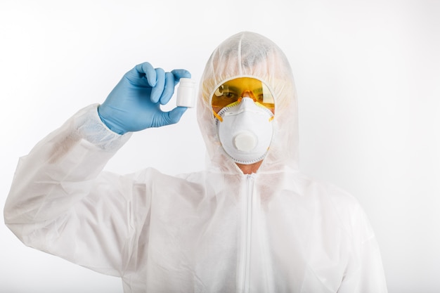 Doctor in anti-epidemic suit holds bottle with pills