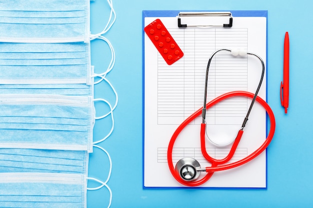 Doctor appointment. Red stethoscope,Medical hygienic masks, tablets, medical documents on doctors workplace in clinic.