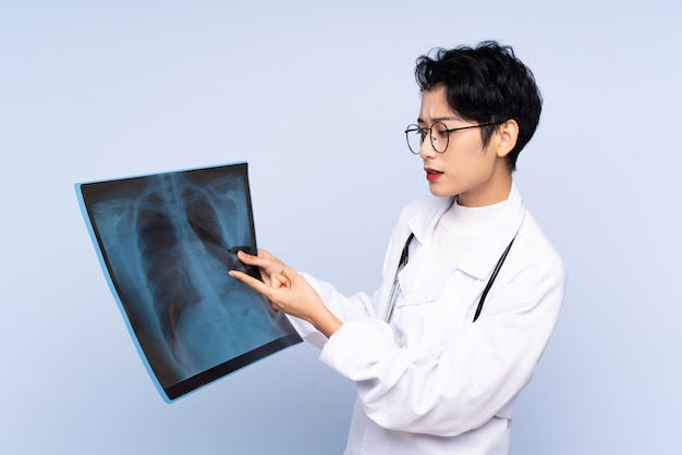 Doctor Asian woman holding a bone scan over isolated blue wall