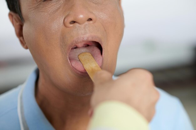 Doctor asking sick patient to open mouth so he could check his throat