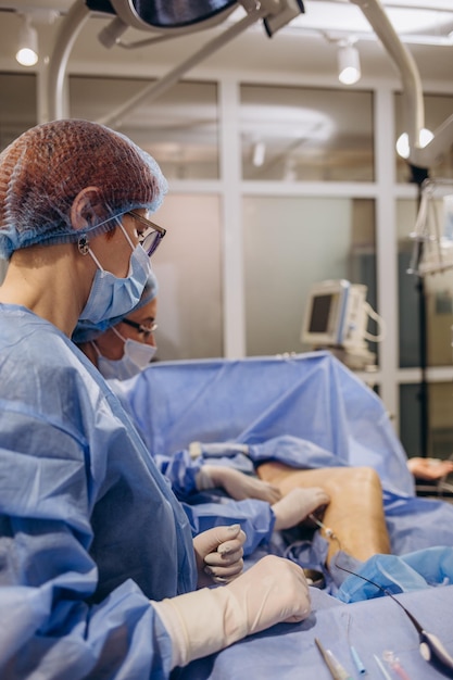 Doctor and an assistant in the operating room for surgical venous vascular surgery clinic