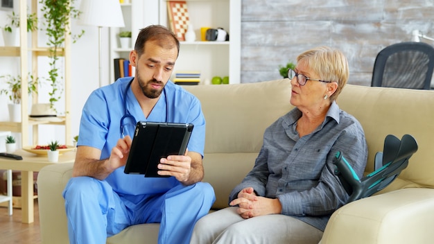 Assistente medico che prende appunti negli appunti mentre ascolta una vecchia donna in pensione nella casa di cura. badante e assistente sociale