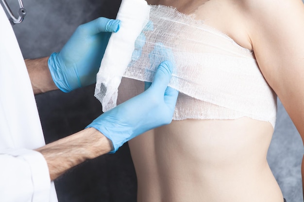 The doctor bandages the woman's chest