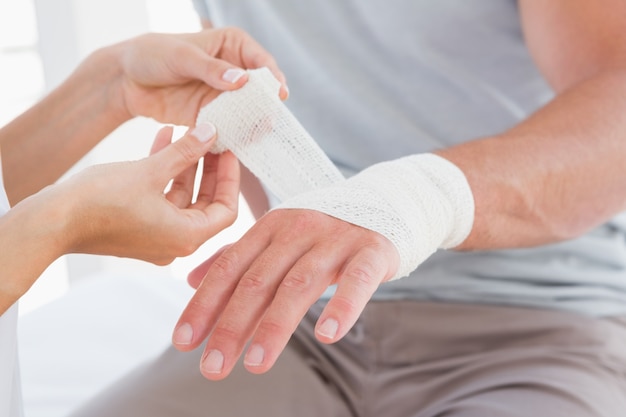 Doctor bandaging her patient hand