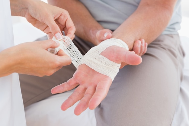 Doctor bandaging her patient hand