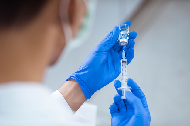 Doctor in blue glove filling syringe with vaccine