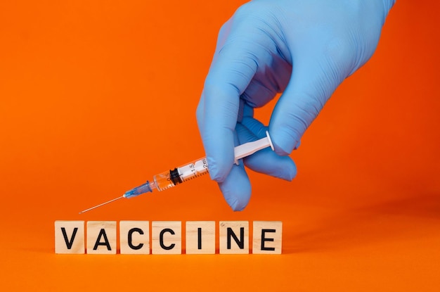 Doctor in blue latex gloves fill in syringe with medicine from glass vial, closeup. Making a vaccine