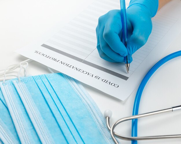 Doctor in blue nitrile gloves fills vaccination protocol