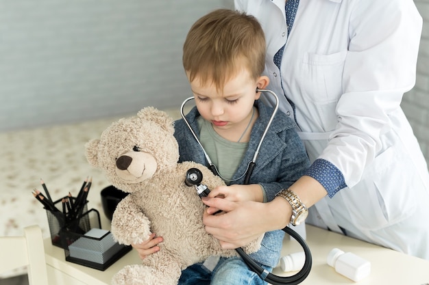 Doctor and boy patient examining teddy bear in Hospital