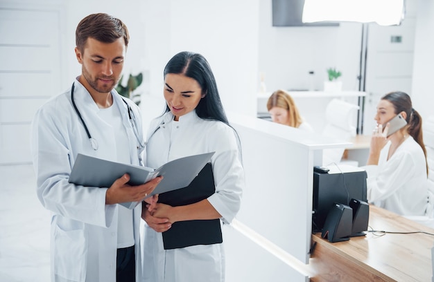 Doctor and brunette nurse stands in the hospital and talking at the work.