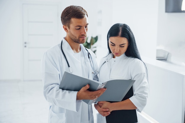 Doctor and brunette nurse stands in the hospital and talking at the work.