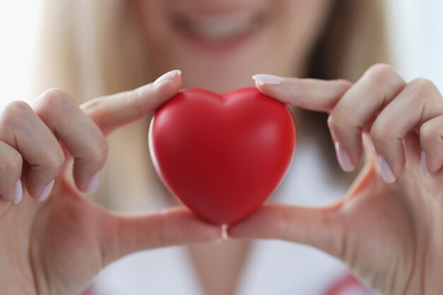 Doctor cardiologist holding red toy heart in his hands closeup. Valentines Day concept