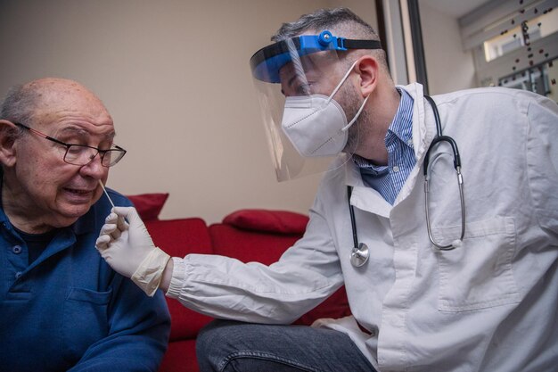 A doctor carries out a coronavirus test with a molecular swab on the nose of an elderly patient