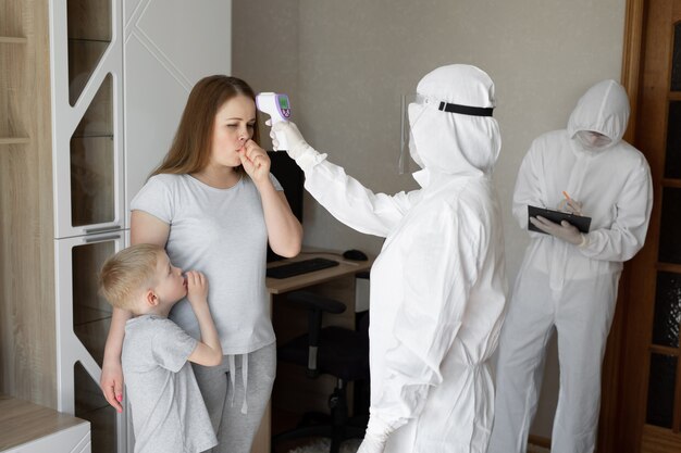 Doctor check patient body temperature using infrared forehead thermometer gun at home. Coronavirus, covid-19, high fever and cough