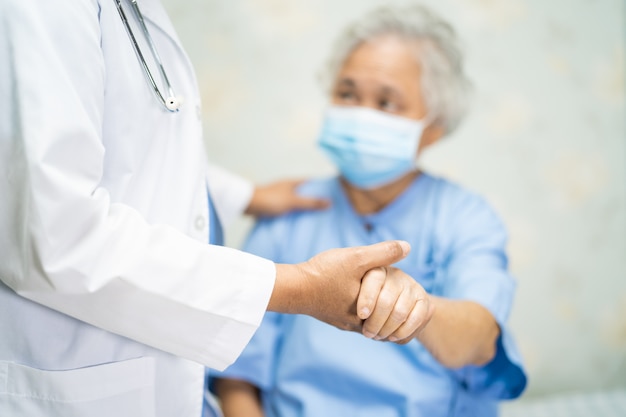 Doctor checking Asian senior woman patient wearing a face mask