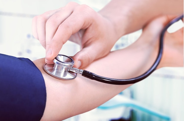 Doctor checking blood pressure of patient , partial view