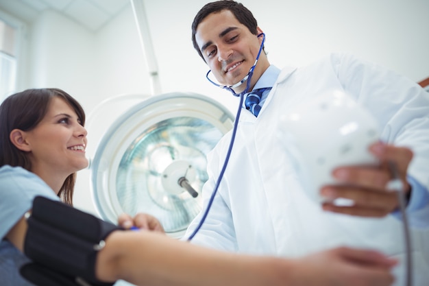 Doctor checking female patient blood pressure