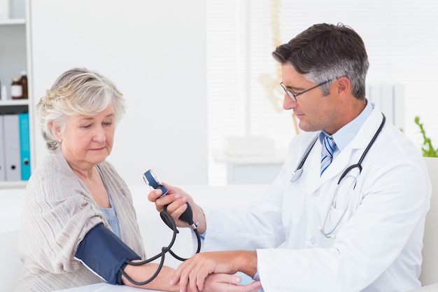 doctor checking female patients blood pressure