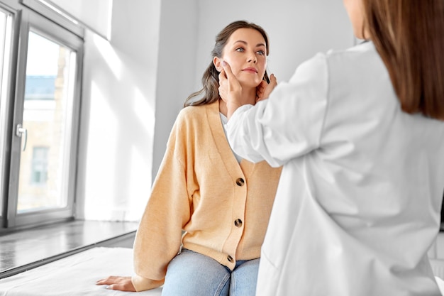 doctor checking lymph nodes of woman at hospital