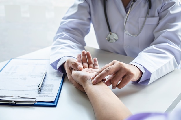 Doctor checking measuring pressure on patients hand pulse by hands