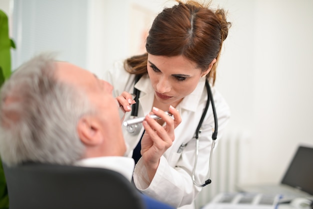 Foto medico che controlla la gola infiammata di un paziente