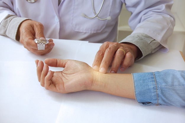 Doctor checking pulse woman patient for heartbeat. Health care concept