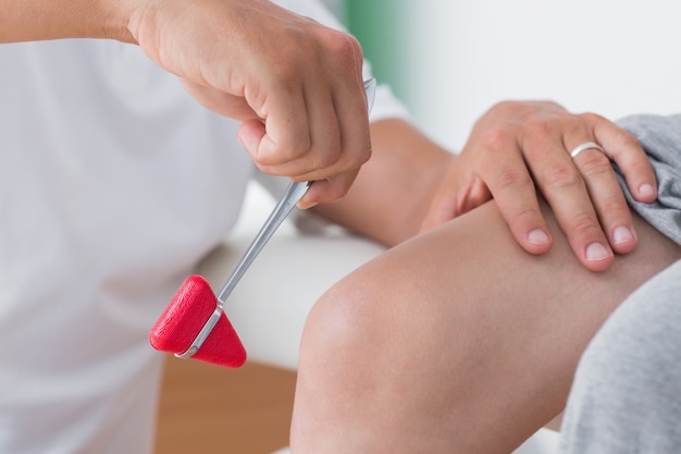 Doctor checking reflexes of the knee of his patient