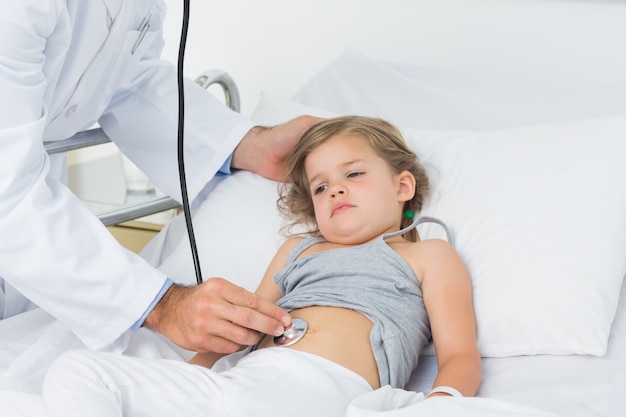 Doctor checking stomach of sick girl