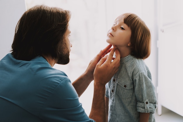 Photo doctor checking up kids lymph nodes carefully