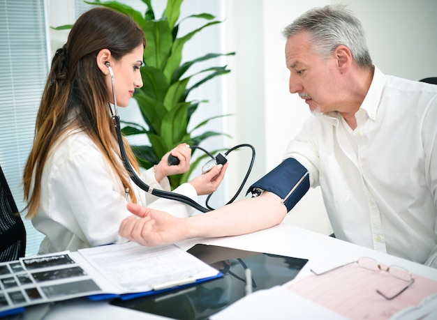 doctor cheking a patients blood pressure