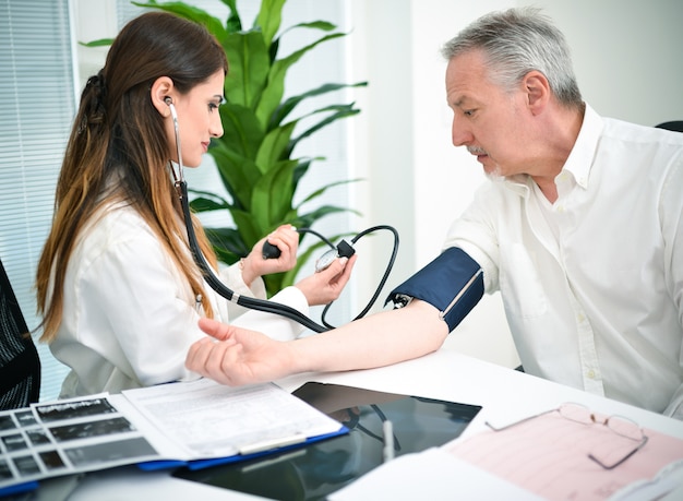 Photo doctor cheking a patients blood pressure