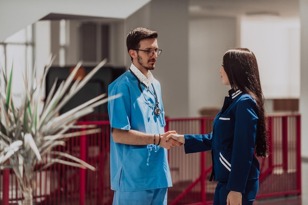 A doctor and the chief nurse of the medical department exchange a handshake in the hallway of a mode