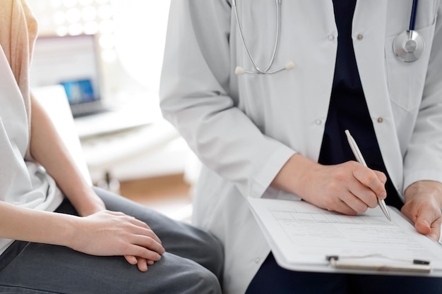 Doctor and child patient. The physician is holding clipboard and writing in medical record form near a boy. The concept of ideal health in medicine.