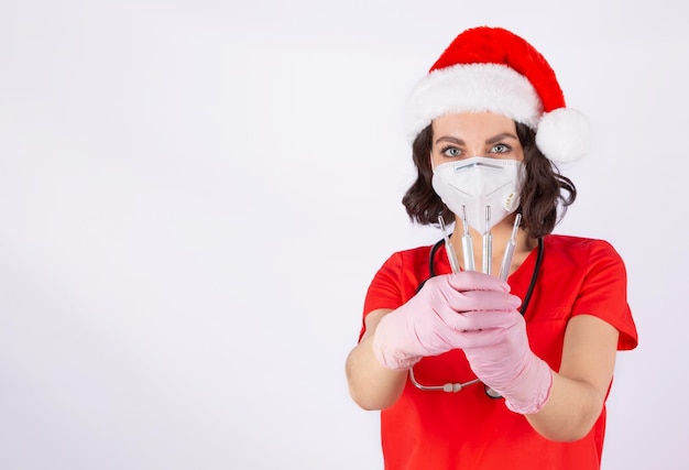 Foto un medico con un cappello di babbo natale tiene in mano termometri a mercurio