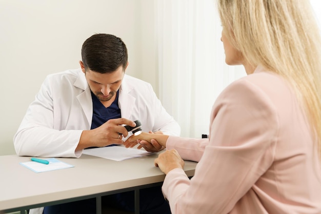 Doctor and client woman in dermatology clinic Dermatologist is using dermatoscope for skin examination