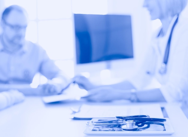 Doctor in clinic asking senior woman in wheelchair for a signature