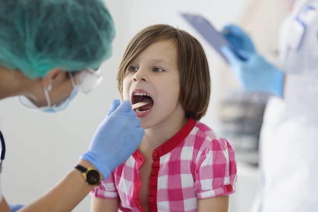 Il dottore in clinica guarda la gola di una ragazza