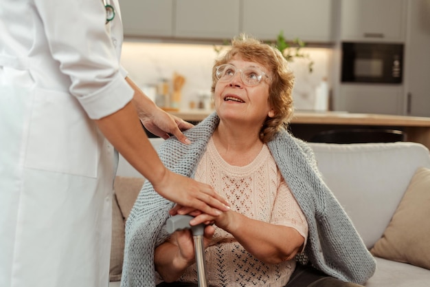 doctor comforting hopeful senior woman holding walking cane