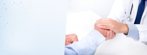 Doctor comforting a patient by holding his hand in the hospital - banner background