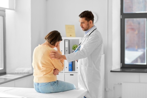 doctor comforting sad woman at hospital