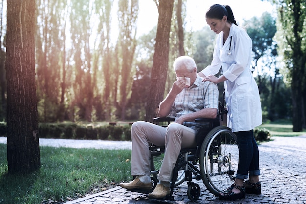 Doctor comforts the crying old man in the summer park