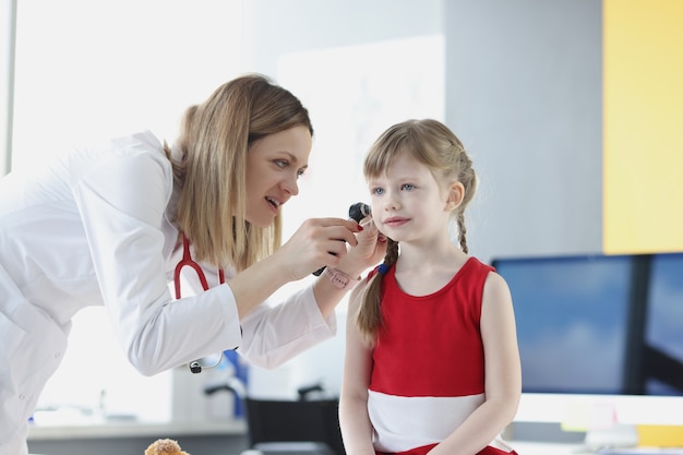 의사는 어린 소녀의 귀의 건강 검진을 실시